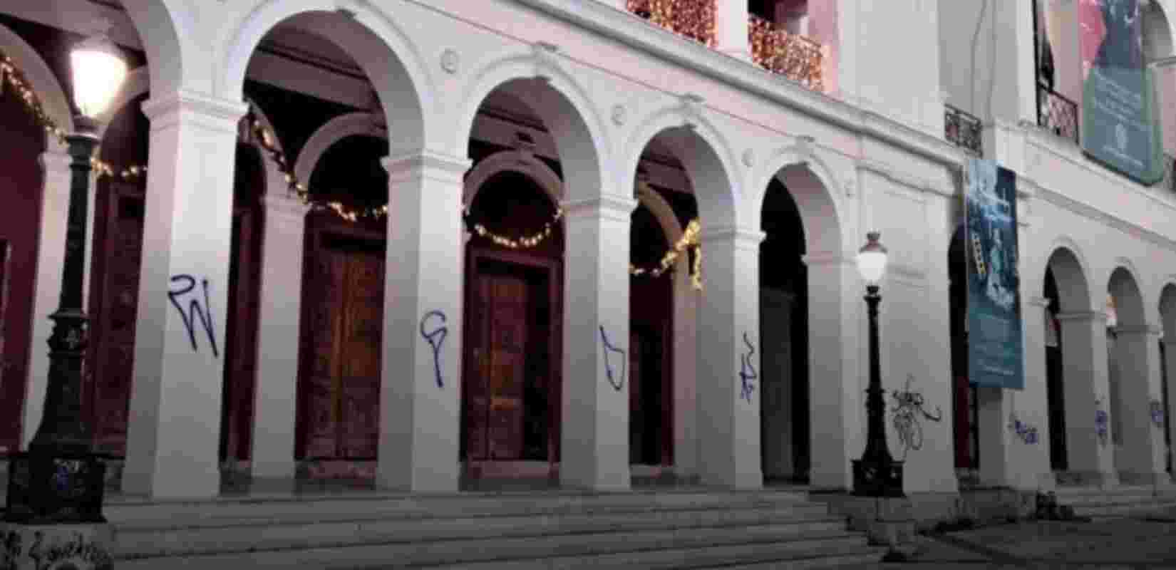Δημοτικό Θέατρο Απόλλων, Apollon Municipal Theatre, Πάτρα, Patras, Ολυμπιακή Φλόγα, Olympic Flame, βανδαλισμοί, vandalism, συνθήματα, graffiti, πολιτιστικό μνημείο, cultural monument, πολιτιστική κληρονομιά Πάτρας, Patras cultural heritage, καθαρισμός θεάτρου, theatre restoration, συντήρηση κτιρίου, building maintenance, φθορές, damage, προστασία δημόσιας περιουσίας, public property protection, δημοτικές υπηρεσίες Πάτρας, Patras municipal services, κέντρο Πάτρας, Patras city center, εκδήλωση Ολυμπιακής Φλόγας, Olympic Flame event, ασφάλεια χώρου, security guarding, φανοστάτης,