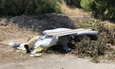 Σωρός από μπάζα, ξερά κλαδιά, στρώματα και απορρίμματα σε υπαίθριο χώρο κοντά σε δέντρα