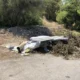 Σωρός από μπάζα, ξερά κλαδιά, στρώματα και απορρίμματα σε υπαίθριο χώρο κοντά σε δέντρα