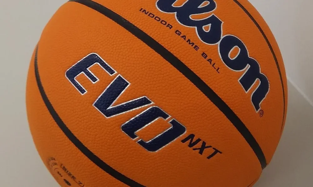 Μπάλα καλαθοσφαίρισης σε πορτοκαλί χρώμα με μαύρες γραμμές και διακριτικά σε κοντινή λήψη.
