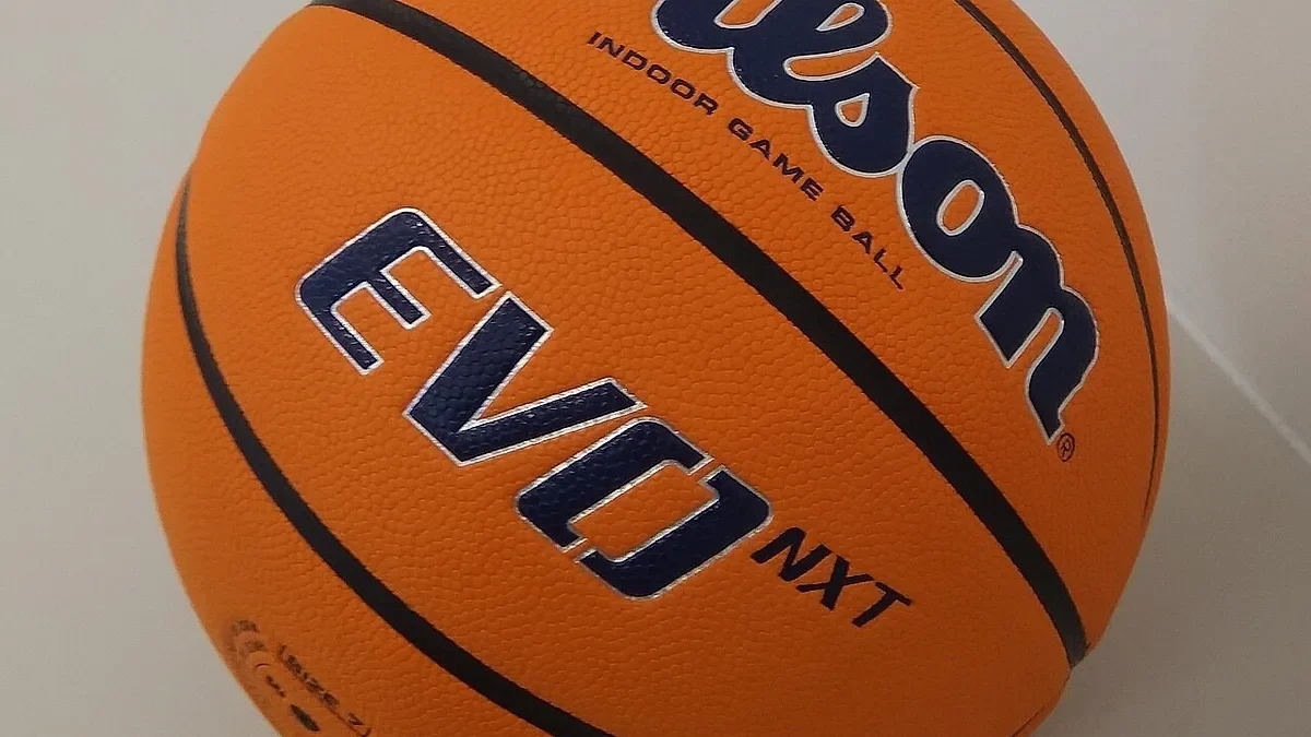 Μπάλα καλαθοσφαίρισης σε πορτοκαλί χρώμα με μαύρες γραμμές και διακριτικά σε κοντινή λήψη.