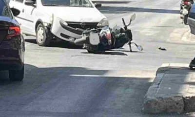 Πτώση δικύκλου στο οδόστρωμα κοντά σε λευκό αυτοκίνητο σε δρόμο.