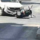 Πτώση δικύκλου στο οδόστρωμα κοντά σε λευκό αυτοκίνητο σε δρόμο.