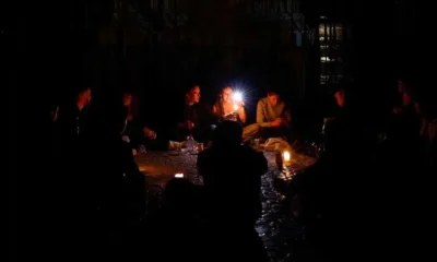 Άτομα καθισμένα σε εξωτερικό χώρο στο σκοτάδι φωτίζονται από κερί