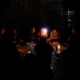 Άτομα καθισμένα σε εξωτερικό χώρο στο σκοτάδι φωτίζονται από κερί