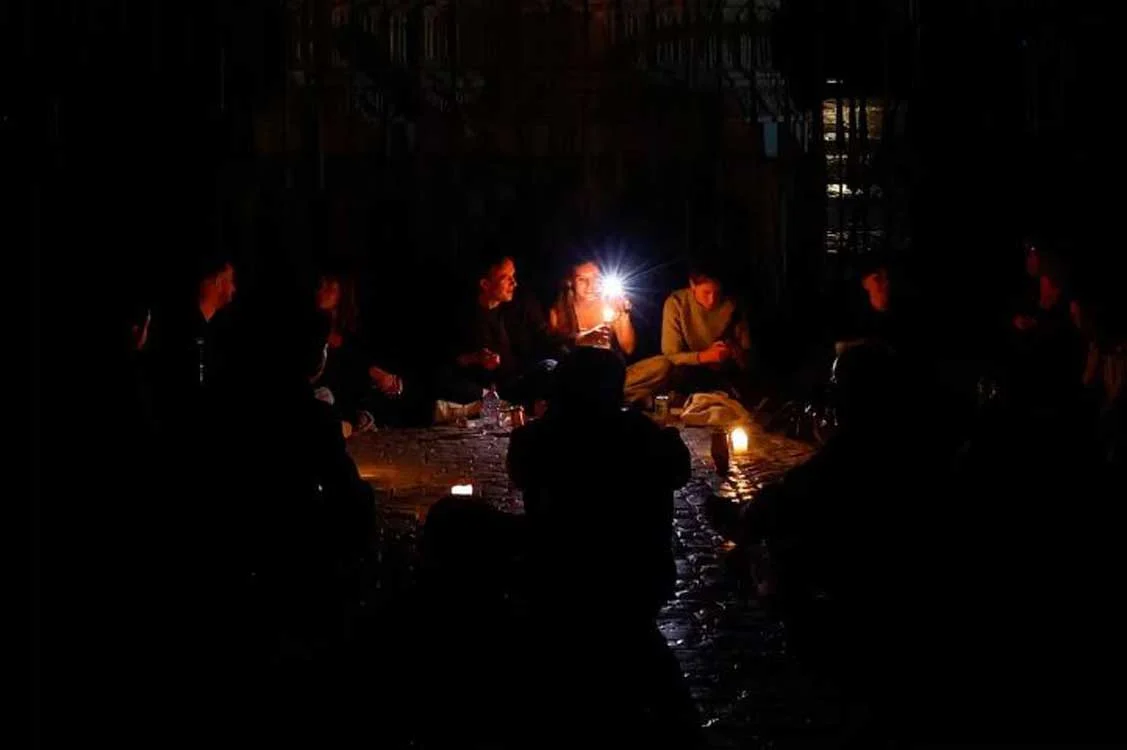 Άτομα καθισμένα σε εξωτερικό χώρο στο σκοτάδι φωτίζονται από κερί