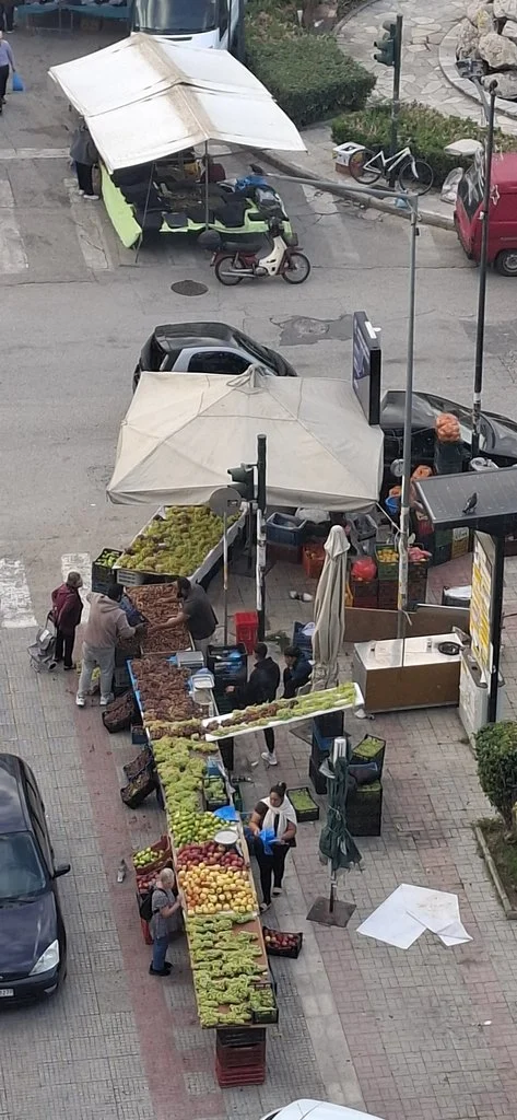 Εναέρια άποψη από πάγκους λαϊκής αγοράς με φρούτα και λαχανικά στημένα σε πεζοδρόμιο και δρόμο