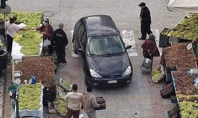 Αεροφωτογραφία δρόμου με πάγκους λαϊκής αγοράς, περαστικούς και ένα αυτοκίνητο.