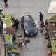 Αεροφωτογραφία δρόμου με πάγκους λαϊκής αγοράς, περαστικούς και ένα αυτοκίνητο.