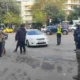 Άτομα και αστυνομικοί σε δρόμο με αυτοκίνητα και κτίρια στο βάθος