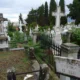 Άποψη νεκροταφείου με μαρμάρινους σταυρούς, τάφους, μεταλλικό φράχτη και επιγραφή σε μαρμάρινη στήλη