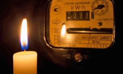 Αναμμένο κερί δίπλα σε αναλογικό μετρητή κατανάλωσης ηλεκτρικής ενέργειας σε σκοτεινό χώρο.