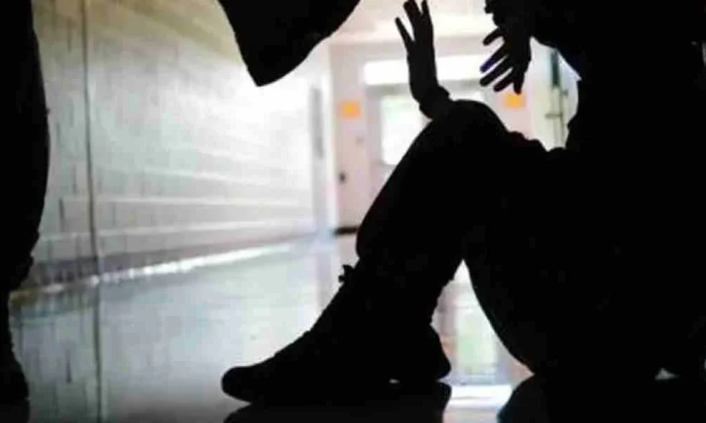 Σιλουέτα ατόμου καθισμένου στο πάτωμα να υψώνει τα χέρια ενώ άλλο άρθρο στέκεται από πάνω του σε διάδρομο.