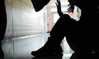 Σιλουέτα ατόμου καθισμένου στο πάτωμα να υψώνει τα χέρια ενώ άλλο άρθρο στέκεται από πάνω του σε διάδρομο.