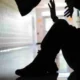 Σιλουέτα ατόμου καθισμένου στο πάτωμα να υψώνει τα χέρια ενώ άλλο άρθρο στέκεται από πάνω του σε διάδρομο.