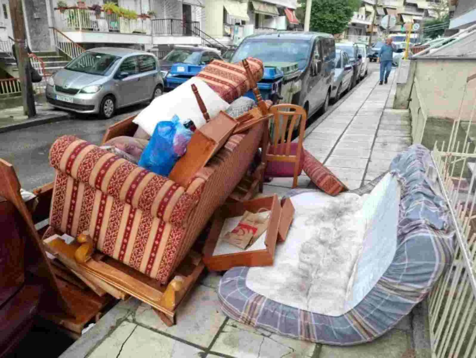 Παλιά έπιπλα και στρώματα πεταμένα σε δρόμο και πεζοδρόμιο δίπλα σε σταθμευμένα αυτοκίνητα