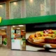 Πρόσοψη καταστήματος με επιγραφή Pizza Fan και μεγάλη φωτογραφία πίτσας στη τζαμαρία