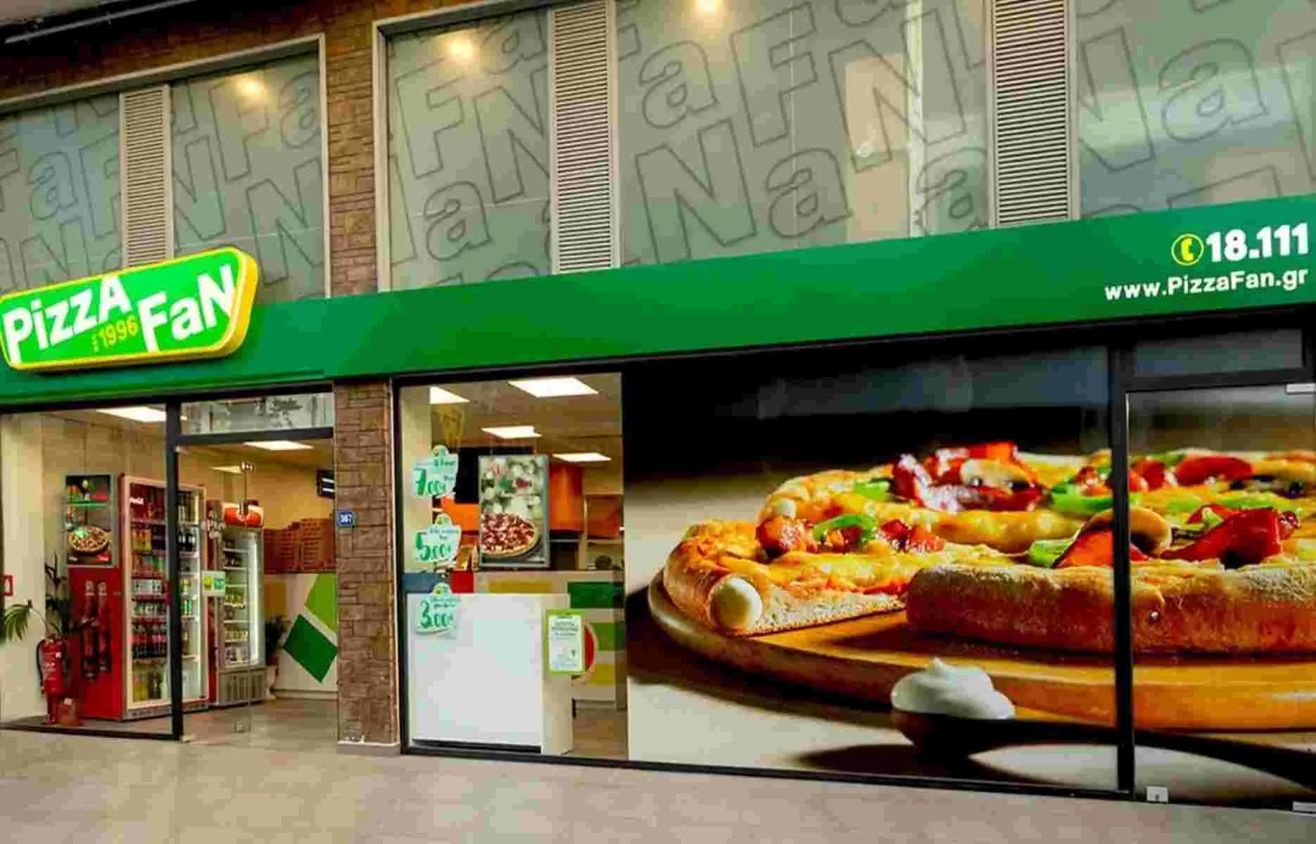Πρόσοψη καταστήματος με επιγραφή Pizza Fan και μεγάλη φωτογραφία πίτσας στη τζαμαρία