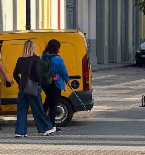 Άτομα κινούνται σε πεζοδρόμηση δίπλα από σταθμευμένο κίτρινο βαν
