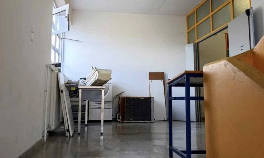 Εσωτερικός χώρος κτιρίου με ανοιχτό παράθυρο, έπιπλα, ηλεκτρονικό εξοπλισμό και αποθηκευμένα αντικείμενα στο πάτωμα.