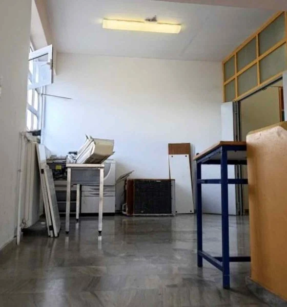 Εσωτερικός χώρος κτιρίου με ανοιχτό παράθυρο, έπιπλα, ηλεκτρονικό εξοπλισμό και αποθηκευμένα αντικείμενα στο πάτωμα.