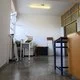 Εσωτερικός χώρος κτιρίου με ανοιχτό παράθυρο, έπιπλα, ηλεκτρονικό εξοπλισμό και αποθηκευμένα αντικείμενα στο πάτωμα.