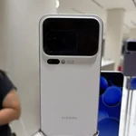 Πίσω όψη λευκού smartphone σε βάθρο έκθεσης, με διπλή οθόνη και κάμερες