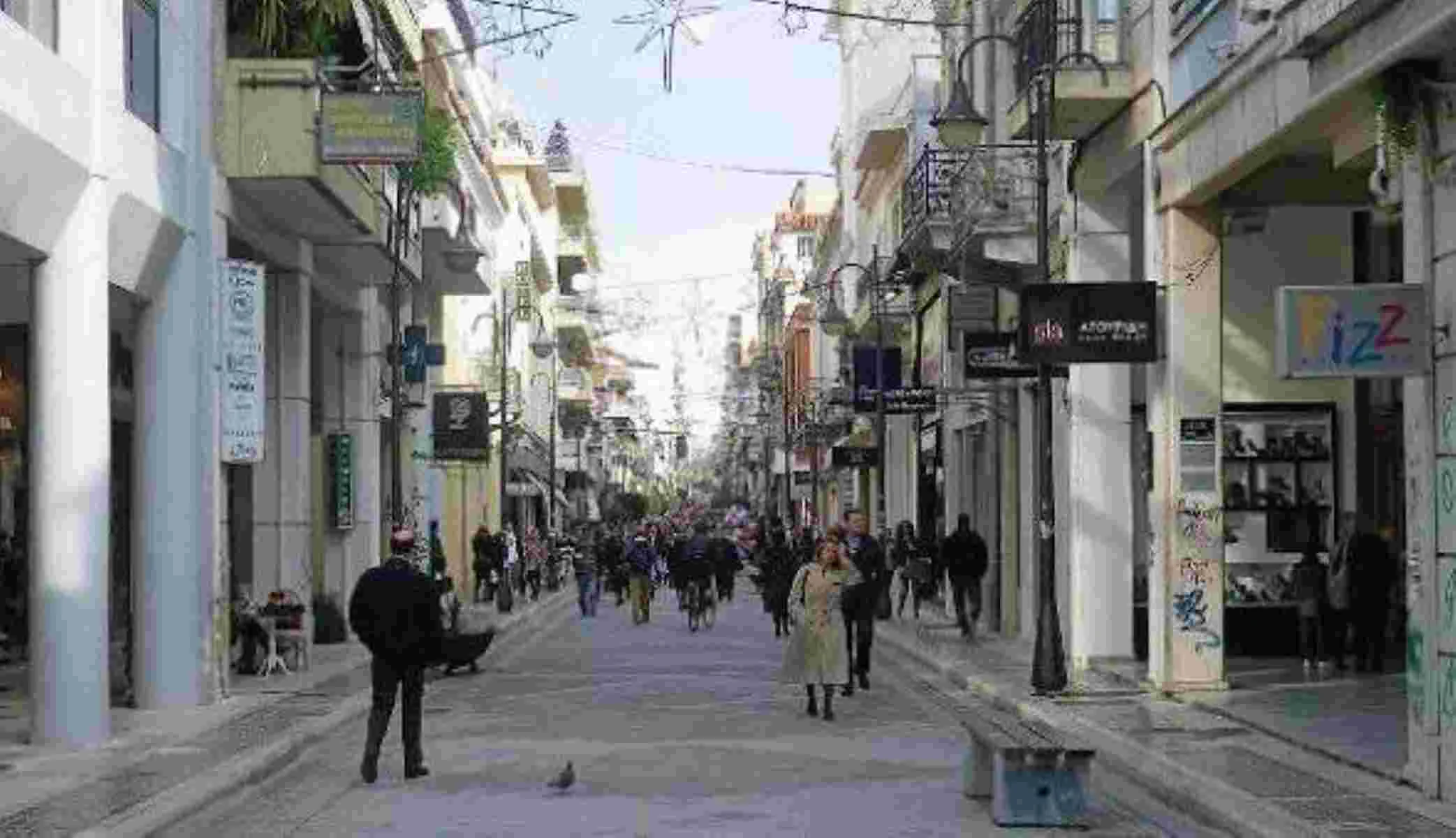 Άποψη πολυσύχναστου εμπορικού δρόμου ανάμεσα σε κτήρια με καταστήματα και πεζούς.