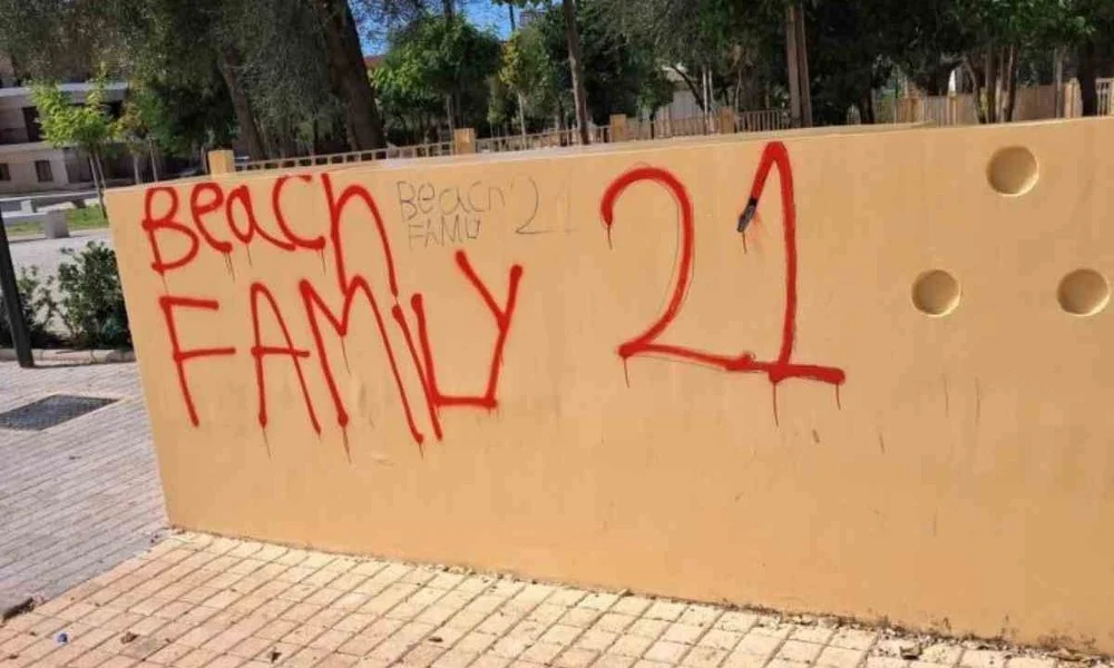 Τοίχος με κόκκινα γκράφιτι σε εξωτερικό χώρο με πλακόστρωτο.