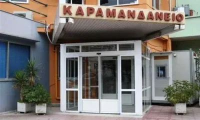 Η είσοδος κτιρίου με γF τζάμια και επιγραφή στα ελληνικά πάνω από τη θύρα.