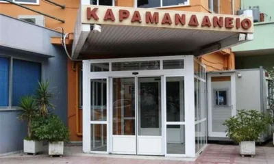 Η είσοδος κτιρίου με γF τζάμια και επιγραφή στα ελληνικά πάνω από τη θύρα.