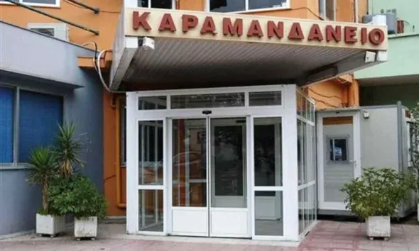Η είσοδος κτιρίου με γF τζάμια και επιγραφή στα ελληνικά πάνω από τη θύρα.