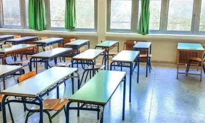 Άδεια σχολική αίθουσα με θρανία, καρέκλες και παράθυρα.