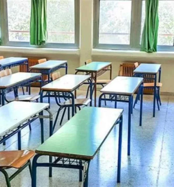 Άδεια σχολική αίθουσα με θρανία, καρέκλες και παράθυρα.