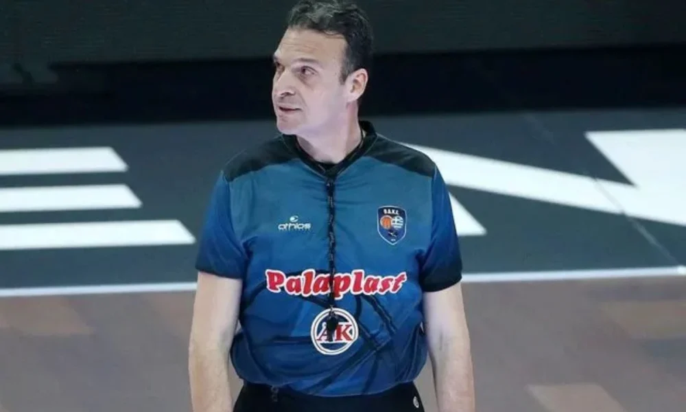 Άνδρας με αθλητικήμφηση διαιτητή καλαθοσφαίρισης βρίσκεται σε κλειστό γήπεδο