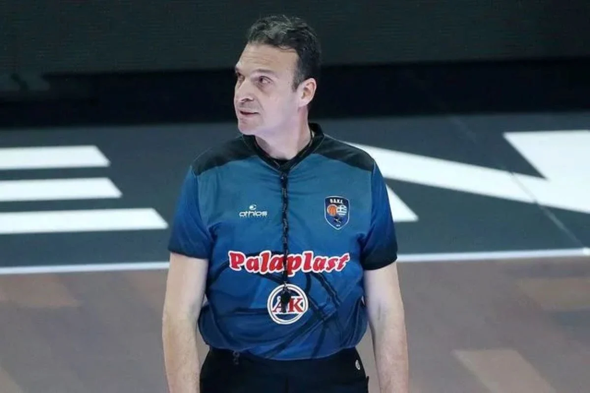 Άνδρας με αθλητικήμφηση διαιτητή καλαθοσφαίρισης βρίσκεται σε κλειστό γήπεδο