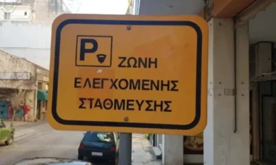 Κίτρινη πινακίδα ζώνης ελεγχόμενης στάθμευσης σε δρόμο πόλης.