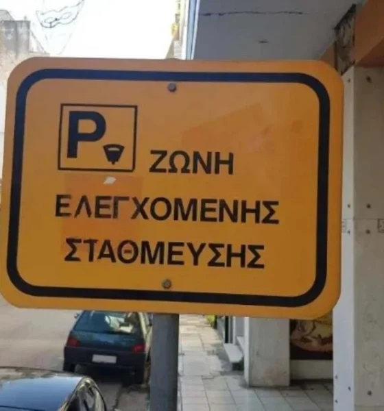 Κίτρινη πινακίδα ζώνης ελεγχόμενης στάθμευσης σε δρόμο πόλης.