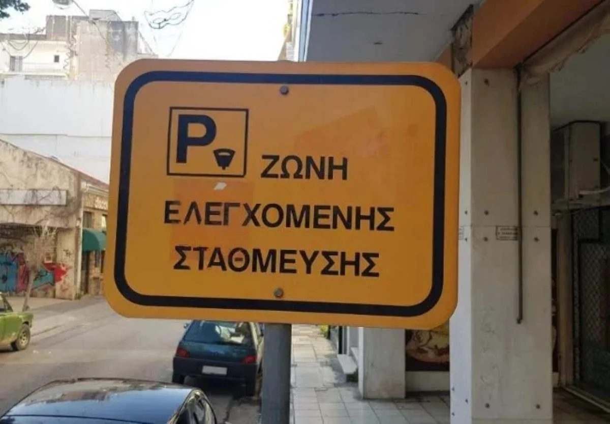 Κίτρινη πινακίδα ζώνης ελεγχόμενης στάθμευσης σε δρόμο πόλης.
