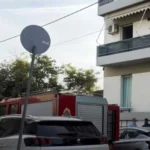 Πυροσβεστικό όχημα έξω από πολυκατοικία με αυτοκίνητα και πινακίδα στον δρόμο