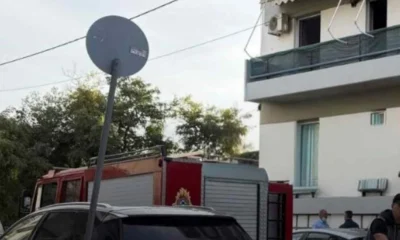 Πυροσβεστικό όχημα έξω από πολυκατοικία με αυτοκίνητα και πινακίδα στον δρόμο