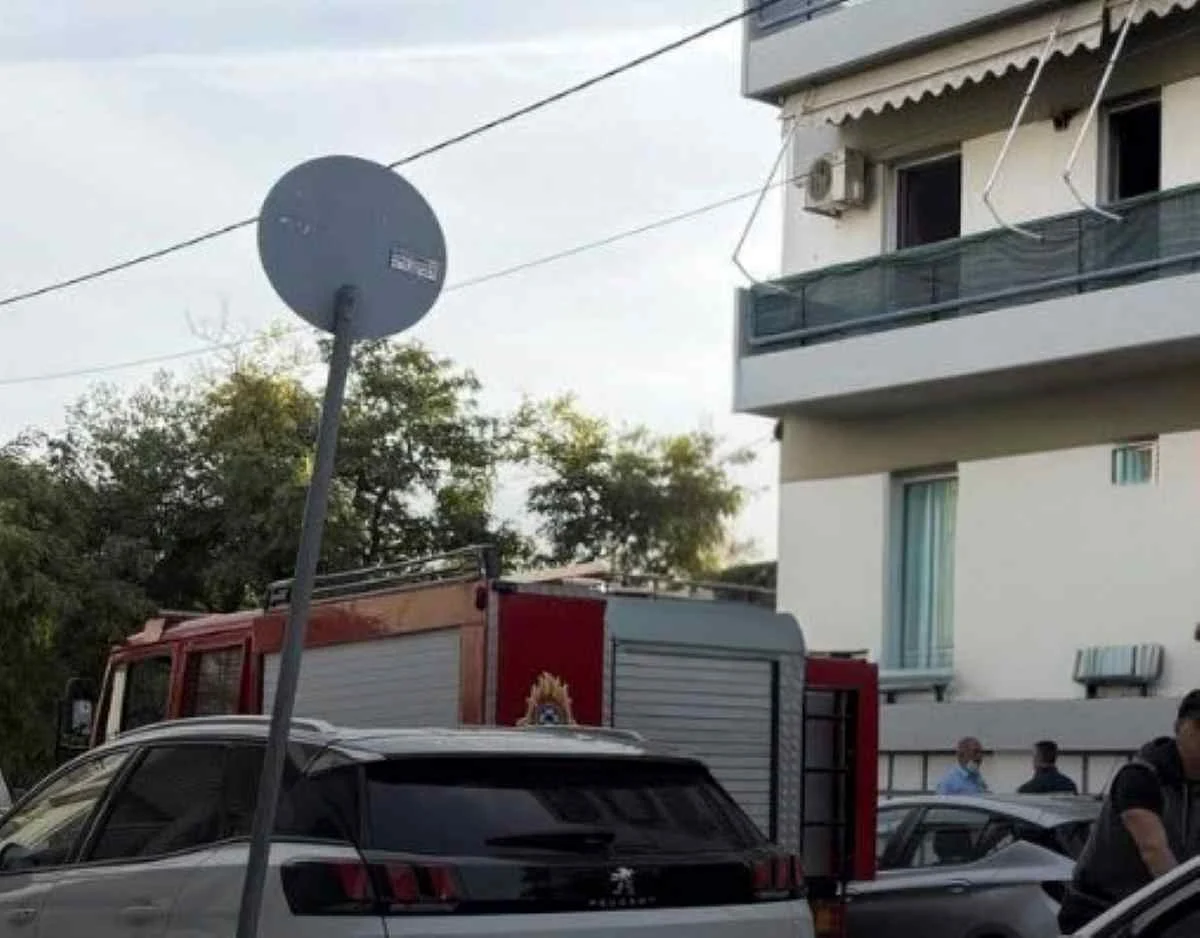 Πυροσβεστικό όχημα έξω από πολυκατοικία με αυτοκίνητα και πινακίδα στον δρόμο