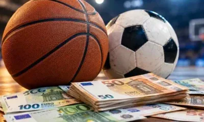 Μπάλα μπάσκετ, μπάλα ποδοσφαίρου και χαρτονομίσματα ευρώ σε ξύλινη επιφάνεια.