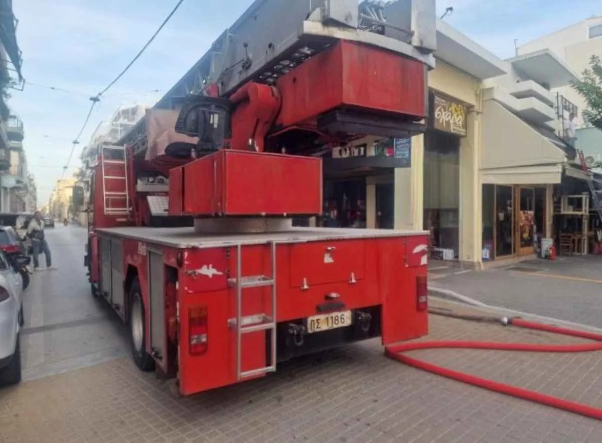 Κόκκινο πυροσβεστικό όχημα σταθμευμένο σε δρόμο μπροστά από καταστήματα