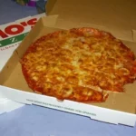 Πίτσα μέσα σε ανοιχτό χάρτινο κουτί delivery πάνω σε τραπέζι