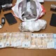 Πάνω σε τραπέζι ακουμπούν χαρτονομίσματα, κινητά τηλέφωνα, κλειδιά και δέματα με πιθανές παράνομες ουσίες.