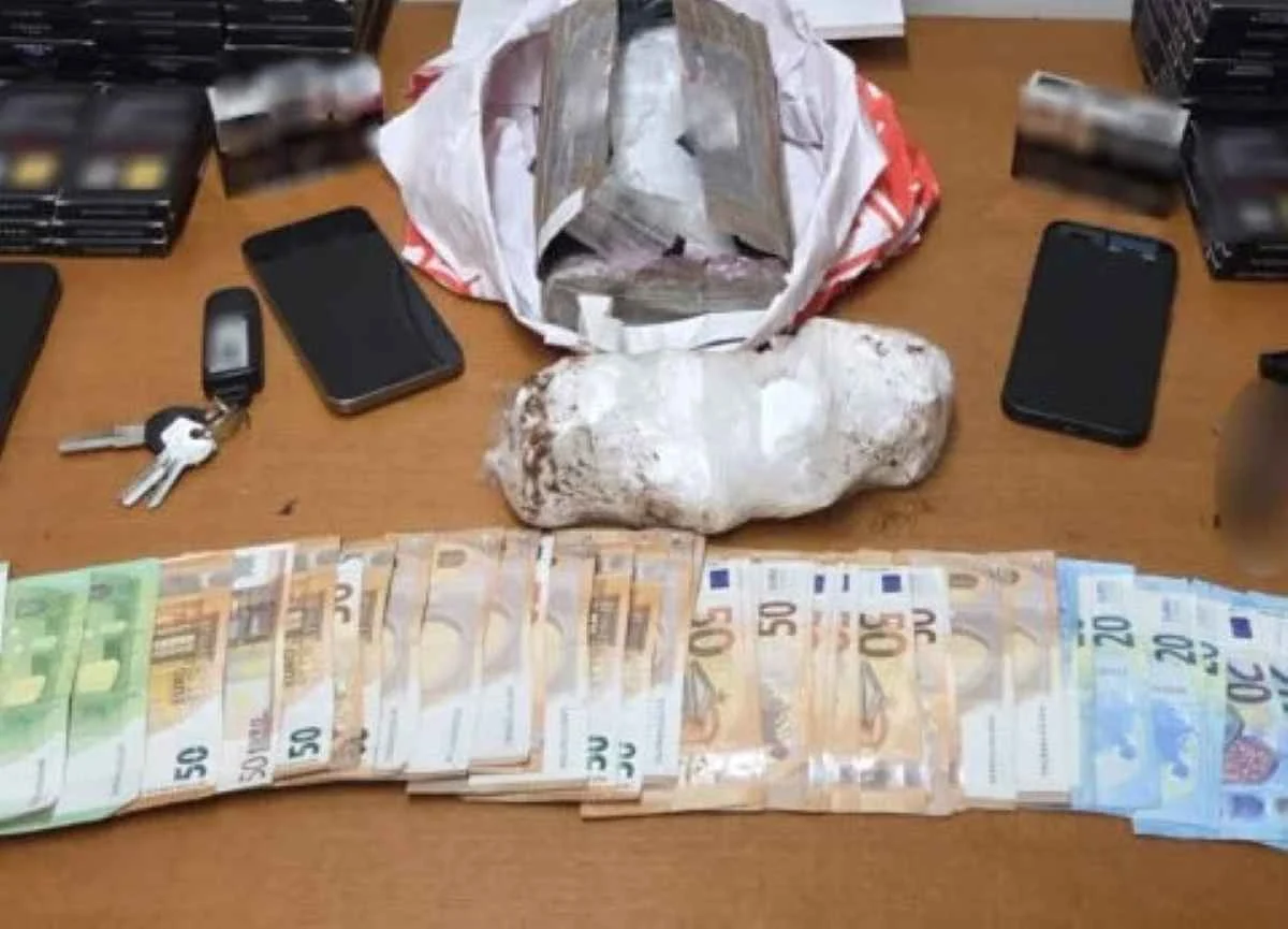 Πάνω σε τραπέζι ακουμπούν χαρτονομίσματα, κινητά τηλέφωνα, κλειδιά και δέματα με πιθανές παράνομες ουσίες.
