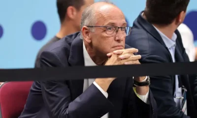 Άντρας με κοστούμι και γυαλιά κάθεται με τα χέρια σταυρωμένα
