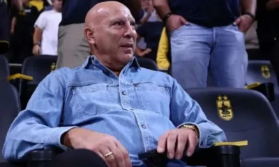 Άντρας κάθεται σε θέση κερκίδας φορώντας τζιν πουκάμισο.