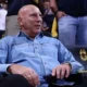 Άντρας κάθεται σε θέση κερκίδας φορώντας τζιν πουκάμισο.